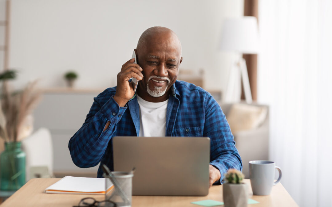 man on his cellphone while using his laptop