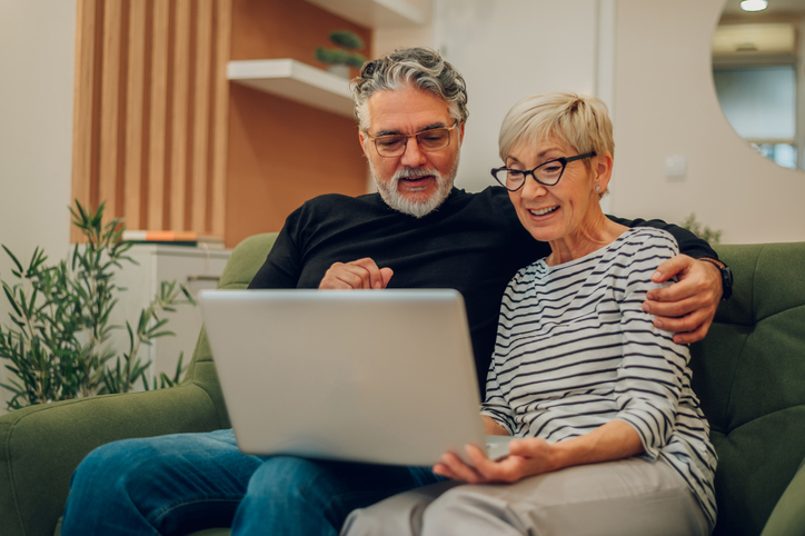 senior couple using a laptop while sitting on a couch at home